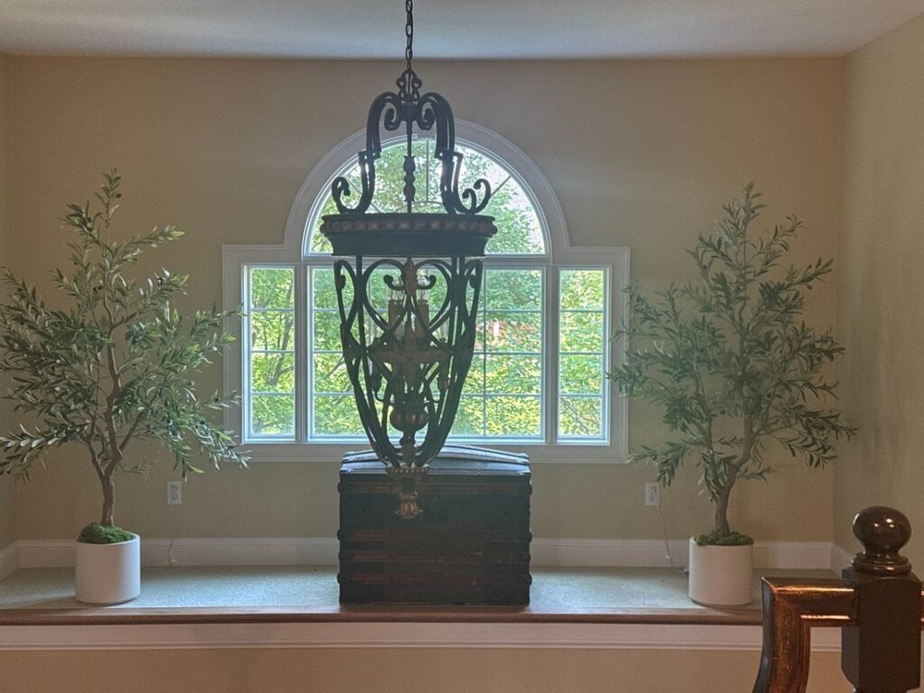 Twin faux olive trees flanking an arched window
