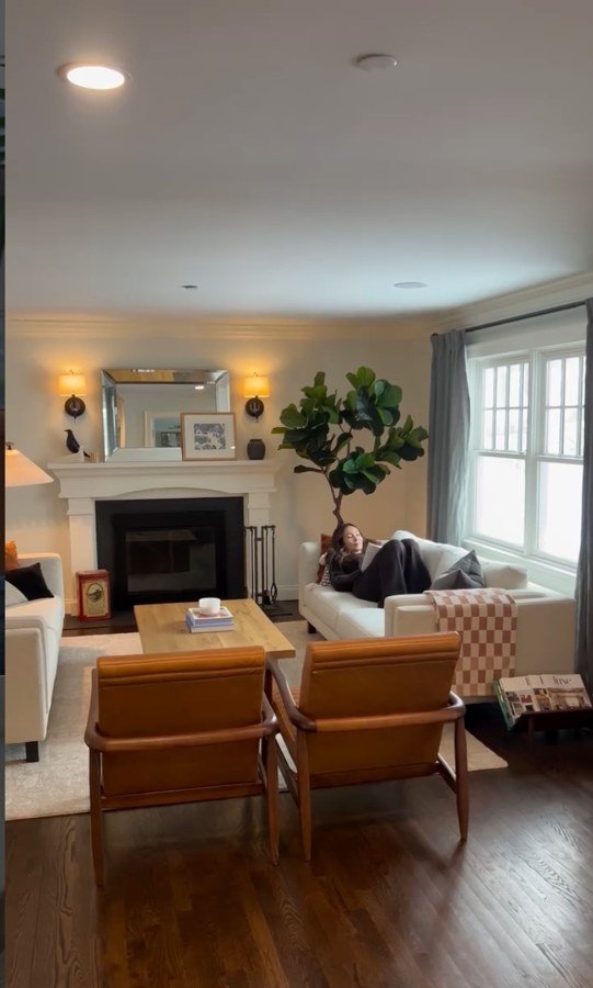 A real customer's living room, showing a tall tree by the window while someone relaxes on the couch