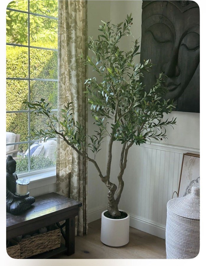 Close-up of a faux olive tree's hand-finished trunk beside a carved wood statue